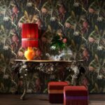 Sfeervolle interieursetting met Arte Blooming Pineapple behang, een sierlijke tafel, oranje lamp en kleurrijke poefjes.