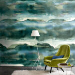 Groene Casamance Iron1 behangwand met een abstract landschapspatroon, gecombineerd met een moderne groene stoel en witte vloerlamp.