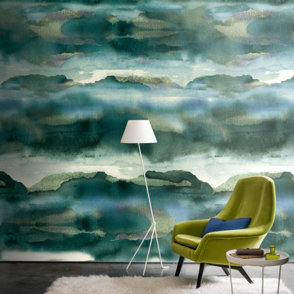 Groene Casamance Iron1 behangwand met een abstract landschapspatroon, gecombineerd met een moderne groene stoel en witte vloerlamp.