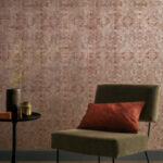 Stijlvolle interieurhoek met Casamance Jali 74420336 behang, een groene stoel en een rood sierkussen.