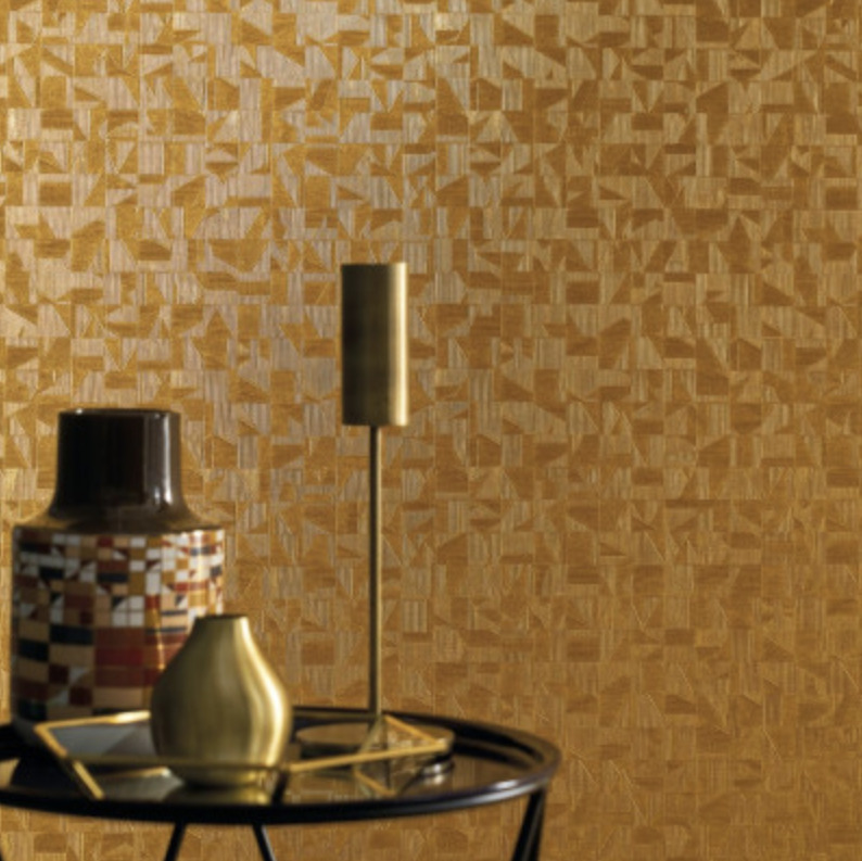 Modern interieur met Casamance Tiznit behang in goudtinten en decoratieve objecten op een zwarte bijzettafel.