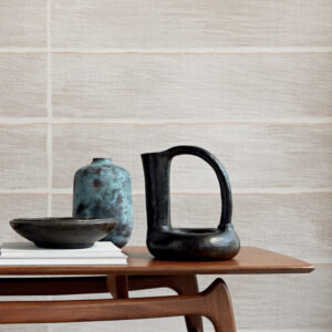 Keramische decorstukken op een houten tafel voor een muur met het textielbehang Caravane Moshi Moshi VP 942 01.