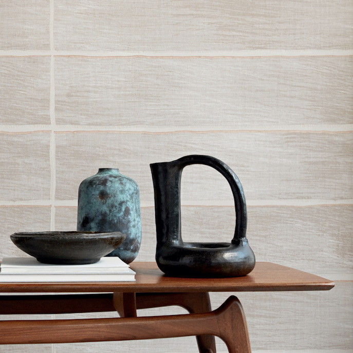 Keramische decorstukken op een houten tafel voor een muur met het textielbehang Caravane Moshi Moshi VP 942 01.