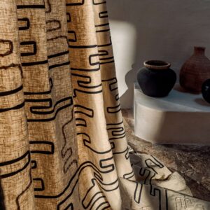 Beige Elitis Baleares Pacha gordijn met zwart abstract patroon in een sfeervol interieur met aardewerken vazen.