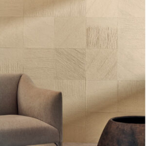 Beige Elitis Hanji Koshi RM 1060 03 behang met textuurpatroon achter een moderne fauteuil en houten decoratief object.