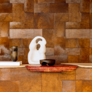Sfeervolle opstelling met Elitis Sauvages behang in warme bruine tinten, decoratief met abstracte sculpturen en keramiek.