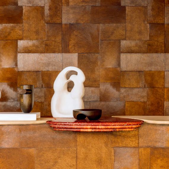 Sfeervolle opstelling met Elitis Sauvages behang in warme bruine tinten, decoratief met abstracte sculpturen en keramiek.