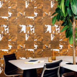 Modern interieur met Elitis Sauvages VP 629 06 behang in koeienhuidlook, een tafel met zwarte stoelen en een grote groene plant.