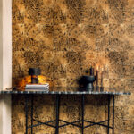 Marmeren consoletafel met decoratieve objecten tegen een goudbruine Elitis Sauvages VP 653 07 behangwand met dierenprintmotief.