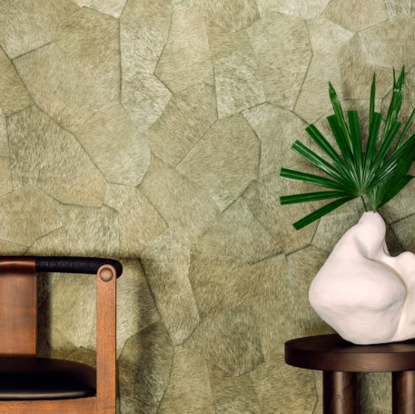Designinterieur met Elitis Sauvages behang, een houten stoel en een kunstzinnige vaas met palmblad op een bijzettafel.