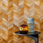 Modern interieur met Elitis Sauvages VP 968 22 behang in visgraatpatroon en decoratieve vazen op een zwarte bijzettafel.