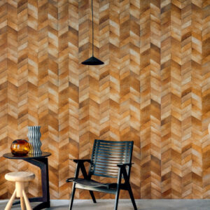 Modern interieur met Elitis Sauvages VP 968 22 behang in warme houttint met visgraatpatroon, zwarte stoel en bijzettafels.