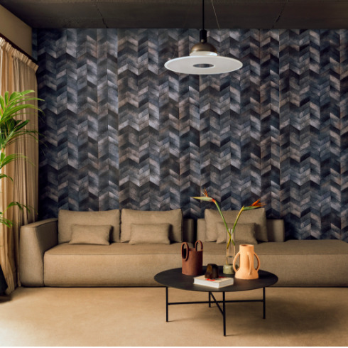 Stijlvolle woonkamer met Elitis Sauvages VP 968 41 behang in donkere visgraatpatronen achter een beige bank en ronde salontafel.