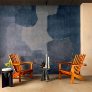 Twee houten stoelen staan tegenover elkaar in een moderne ruimte met Elitis Sauvages VP 973 03 behang in blauwgrijze tinten op de achterwand.