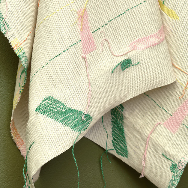 Detail van de Elitis Excentric Bowie stof met kleurrijke geometrische borduursels op een grove, beige ondergrond.