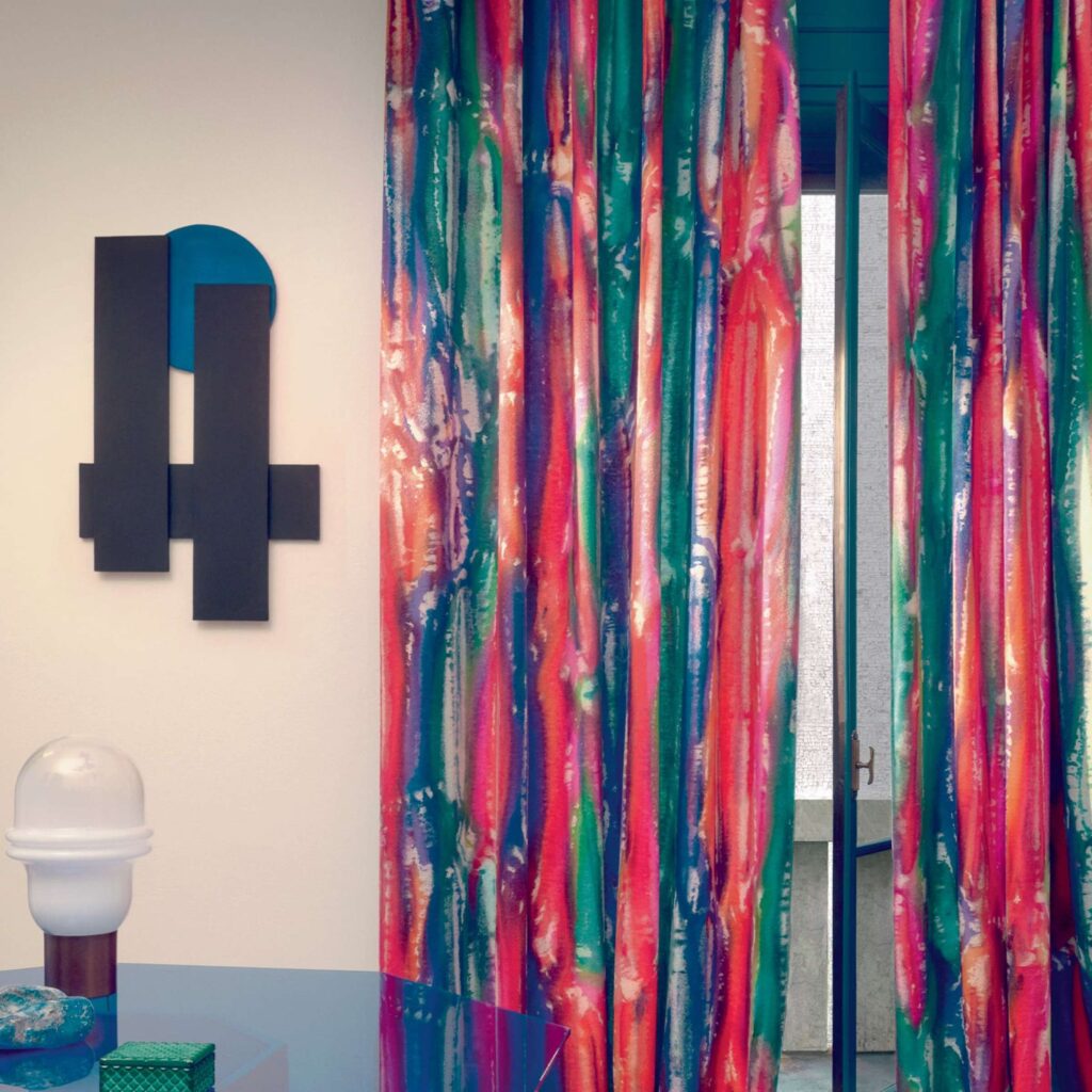 Kleurrijke Elitis Excentric Funky gordijnen in een modern interieur met abstracte wanddecoratie en designlamp.
