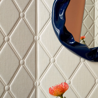 Reliefbehang Elitis Forms Wall Mone Lin RM 1057 01 met ruitpatroon, een blauwe organische spiegelrand en een oranje bloem op de voorgrond.