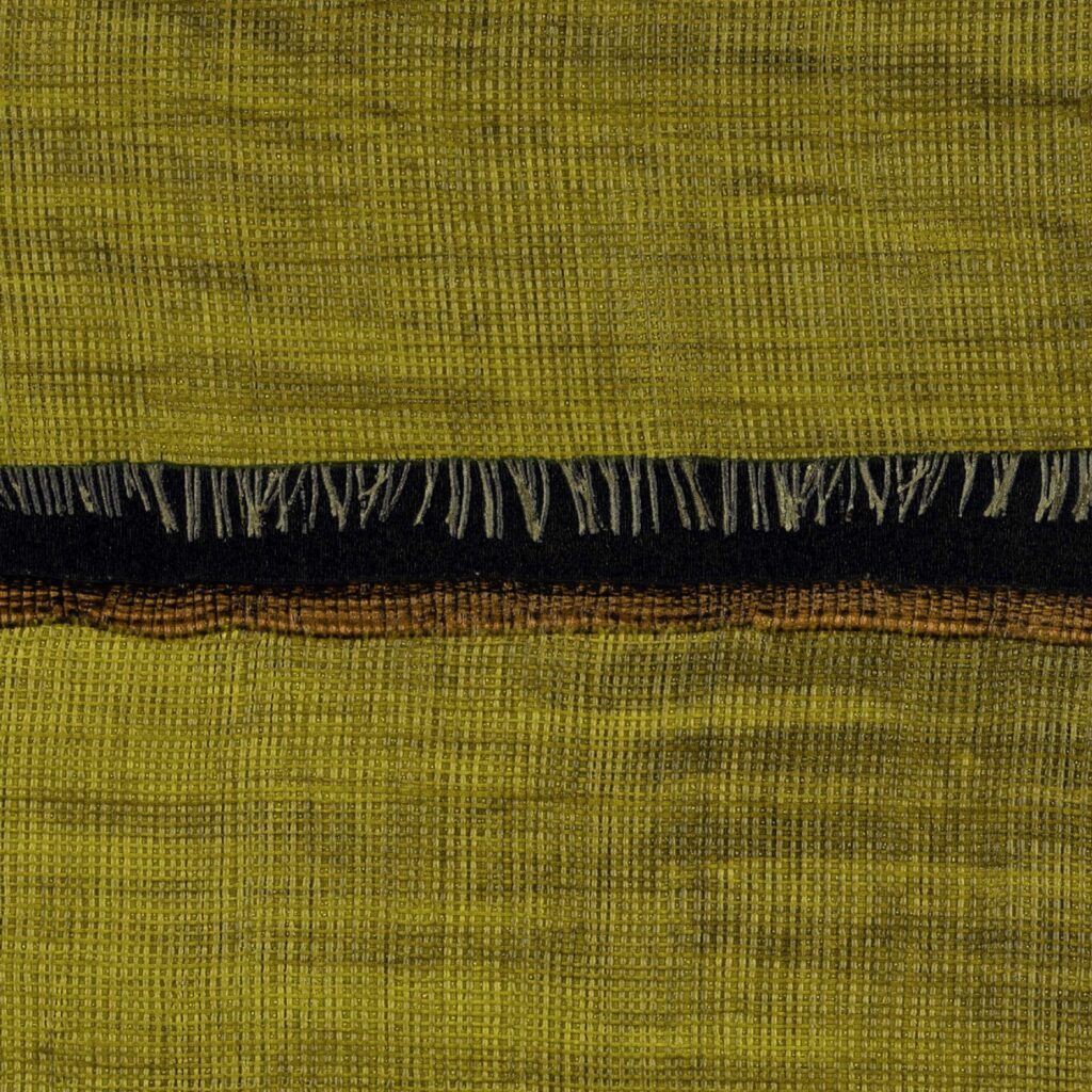 Geweven textiel in mosterdgele tint met zwarte en bruine accenten uit de Elitis La Caravane Moshi Moshi VP 942 06 collectie.