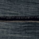 Detail van een donkerblauw textiel met een geruit weefpatroon en franjes, uit de Elitis La Caravane Moshi Moshi VP 942 12 collectie.