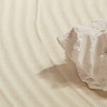 Grote witte steen op beige Elitis Le Jardin d’Aloès Palimpseste linnen stof met subtiel golvend reliëf.