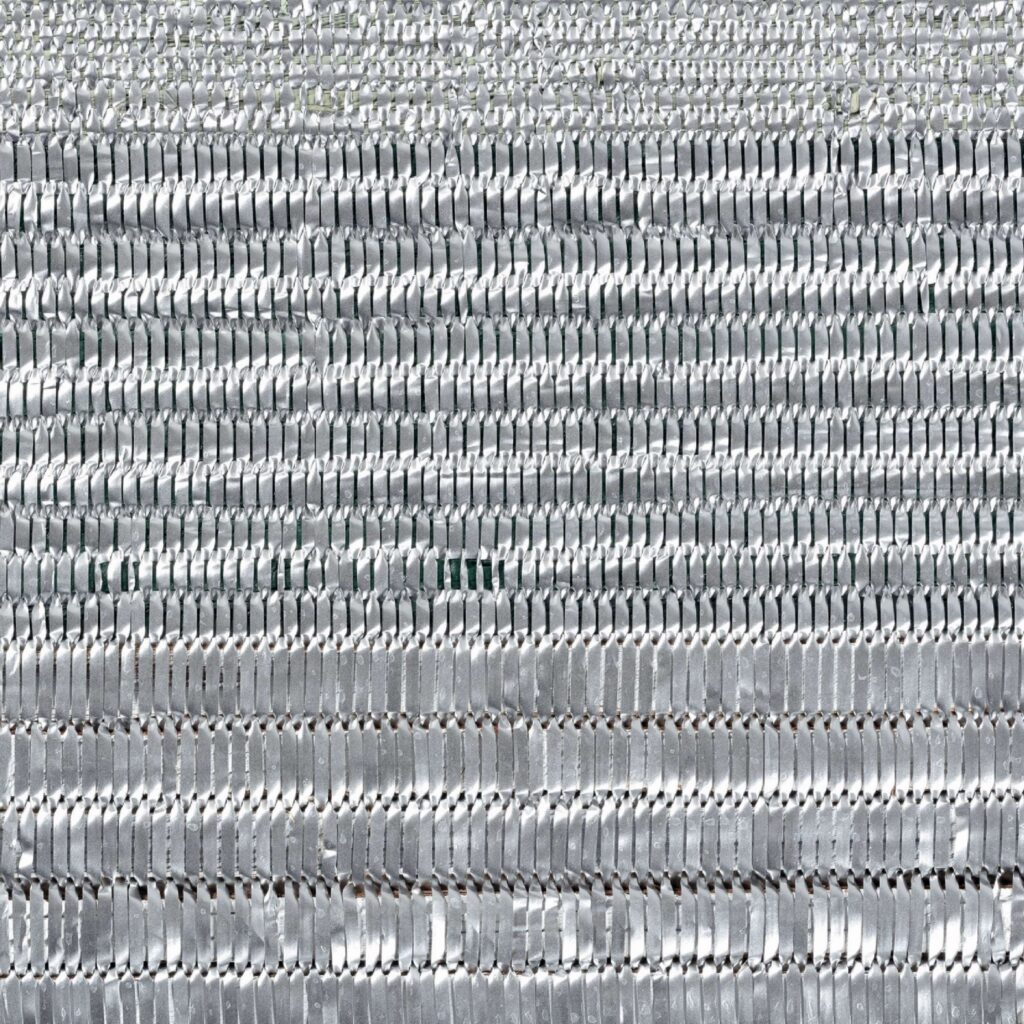 Close-up van het Elitis SOLO Wall Silver RM 1007 90 behang met een geweven, glanzend zilveren textuur.
