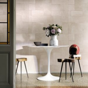 Moderne interieursetting met Elitis Indomptee Appaloosa VP 618 07 behang, ronde witte tafel, bloemenvaas en designkrukken.