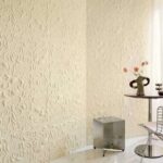 Beige reliëfbehang met organisch patroon uit de collectie Le Jardin d’Aloès siert een moderne, lichte interieurhoek.
