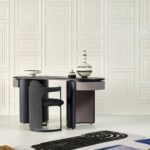 Modern interieur met een zwarte designstoel en tafel voor een wand met klassiek ogend Manoir Arte-behang.