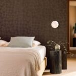 Moderne slaapkamer met een sculpturaal donkerhouten muurpaneel, minimalistische verlichting en een stijlvol nachtkastje met vaas.