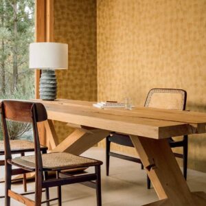 Houten eettafel met rotan stoelen in een interieur met mural bois sculpté volute behang.