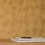 Decoratief behang met houtnerf-patroon in volute-stijl achter een stapel notitieboeken en een potlood op een houten oppervlak.