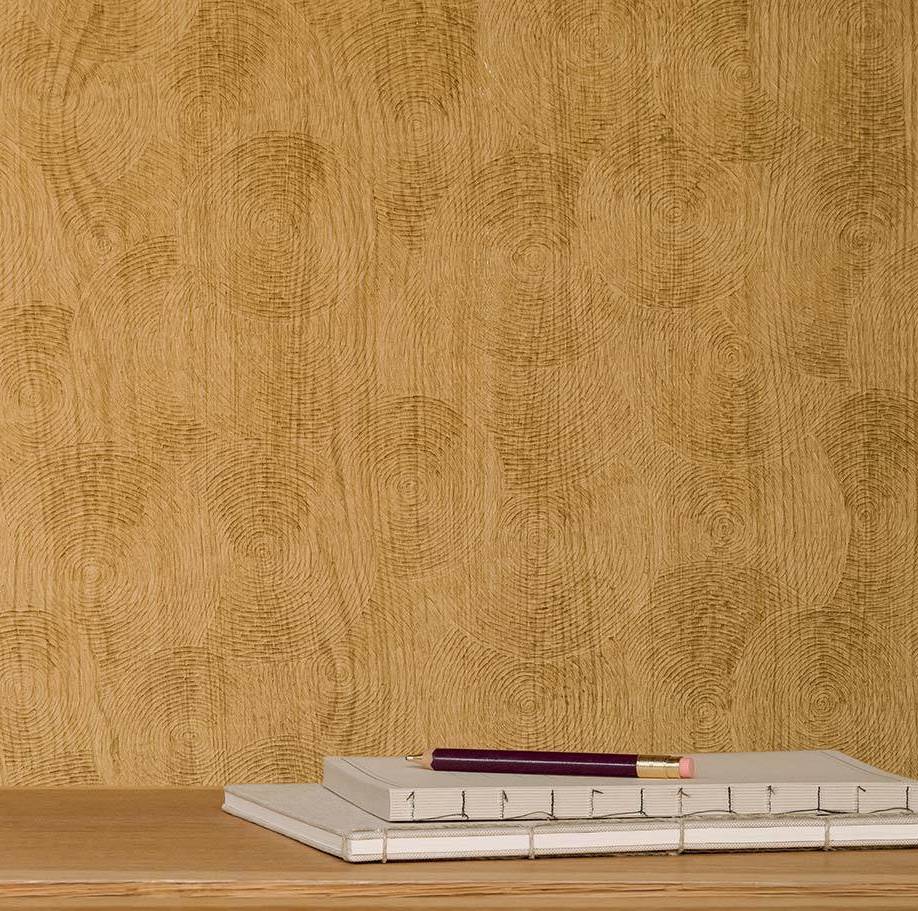 Decoratief behang met houtnerf-patroon in volute-stijl achter een stapel notitieboeken en een potlood op een houten oppervlak.