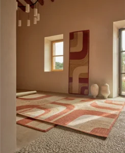 Vloerkleden met een retro print in aardetinten liggen in een minimalistische, warm ingerichte ruimte.