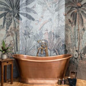 Vrijstaand koperen bad met gouden kraan voor een sfeervolle muur met junglebehang uit de Arte 97630 collectie.