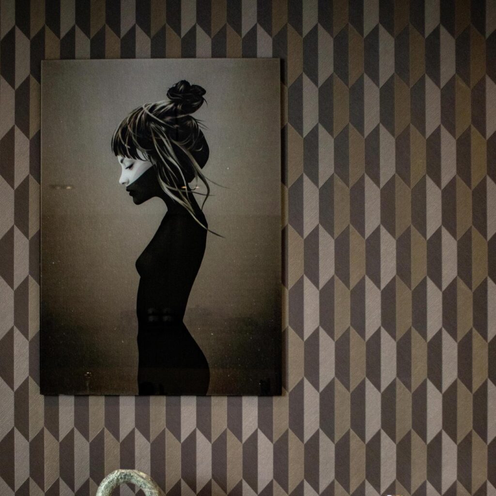 Schilderij van een gestileerde vrouw in profiel aan de muur met Arte Arrow 26523 behang op de achtergrond.