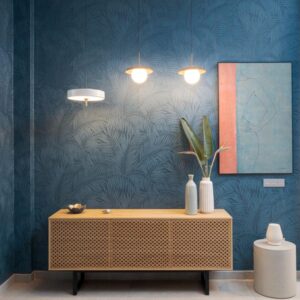 Moderne interieurhoek met Arte Sabal blauw behang, rotan dressoir, hanglampen en minimalistische decoratie.