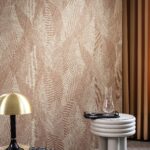 Moderne interieurhoek met Arte Essentials Tangram Bounty 24021 behang in een warm patroon, een ronde bijzettafel met glaswerk en een messing tafellamp.