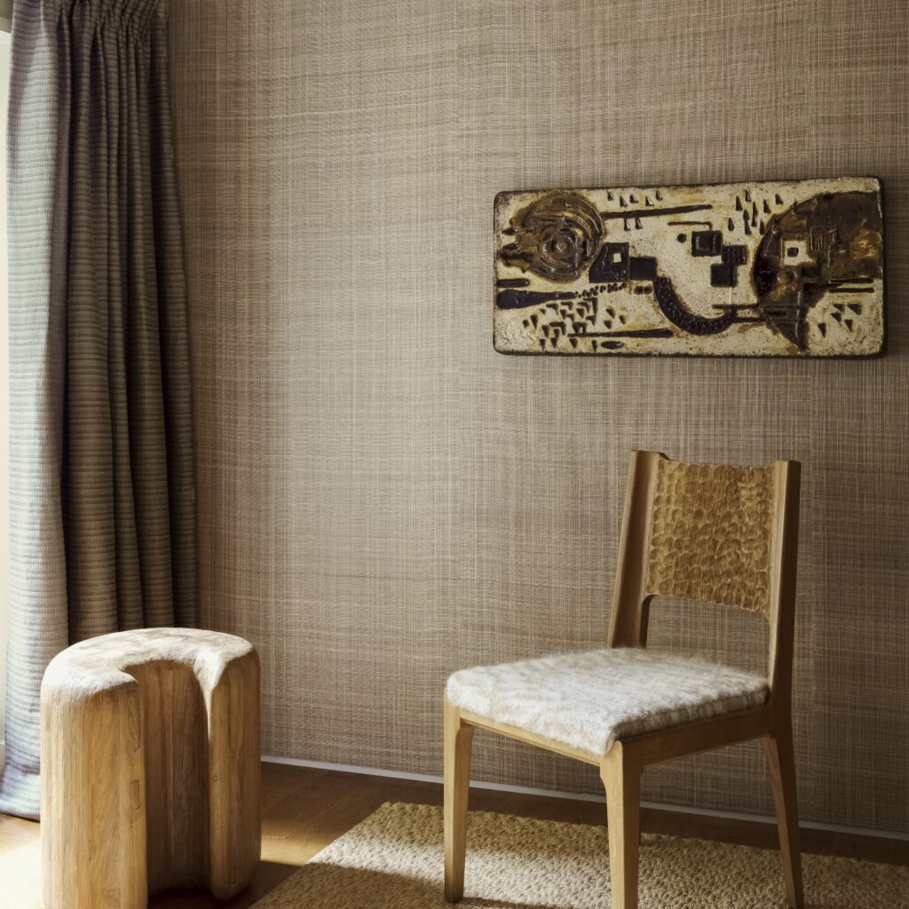 Sfeervolle interieurhoek met Arte Diffuse 52441 behang, een houten stoel, kunstwerk aan de muur en een organisch gevormd houten krukje.