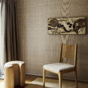 Sfeervolle interieurhoek met Arte Diffuse 52441 behang, een houten stoel, kunstwerk aan de muur en een organisch gevormd houten krukje.