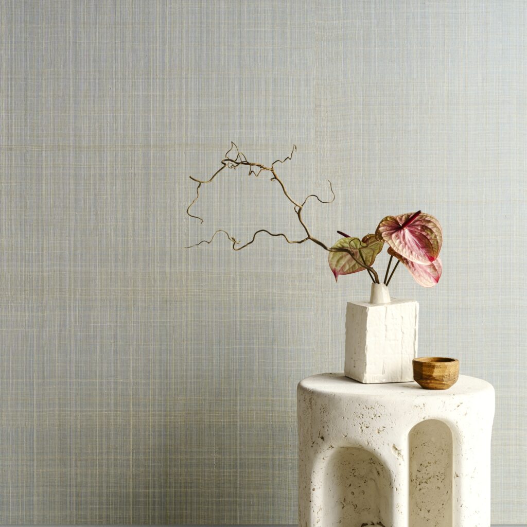 Minimalistisch interieur met Arte Diffuse 52443 behang, een witte vaas met sierlijke takken en roze-groene bladeren op een licht stenen tafeltje.