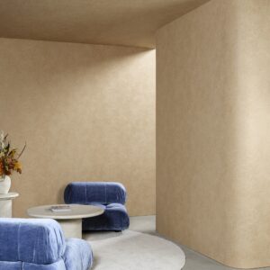 Minimalistisch interieur met beige Calcaire Stucco-muurbekleding uit de Arte Essentials Kaolin collectie, blauwe fluwelen stoelen en een ronde tafel.