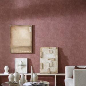 Interieur met Arte Essentials Kaolin Calcaire Stucco muur in roodtint, decoratieve vazen en abstracte kunstwerken.