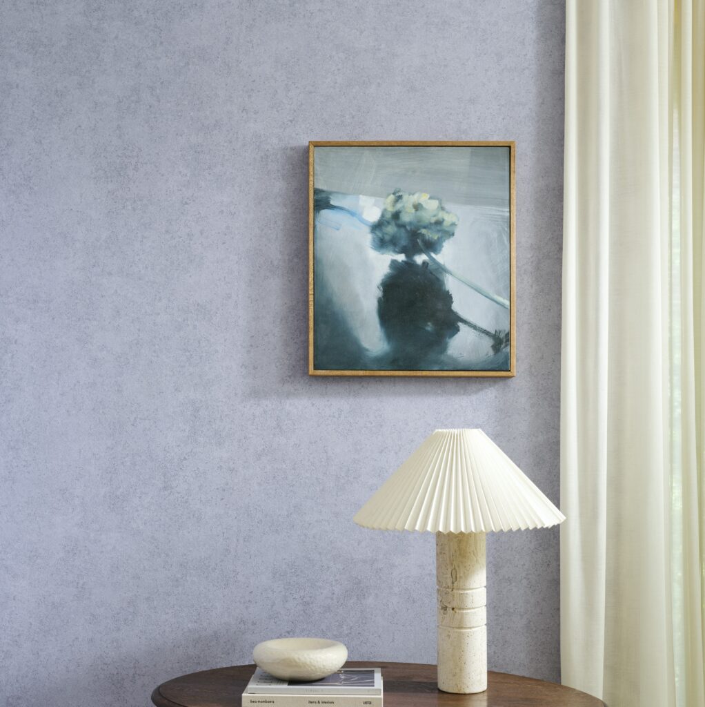 Sfeervolle ruimte met Arte Essentials Kaolin Calcaire Stucco muur, een schilderij, een designlamp en een ronde tafel.
