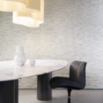 Moderne interieursetting met Arte Matiz 73520A behang, marmeren tafel, zwarte stoel en strakke witte keramiekdecoratie.