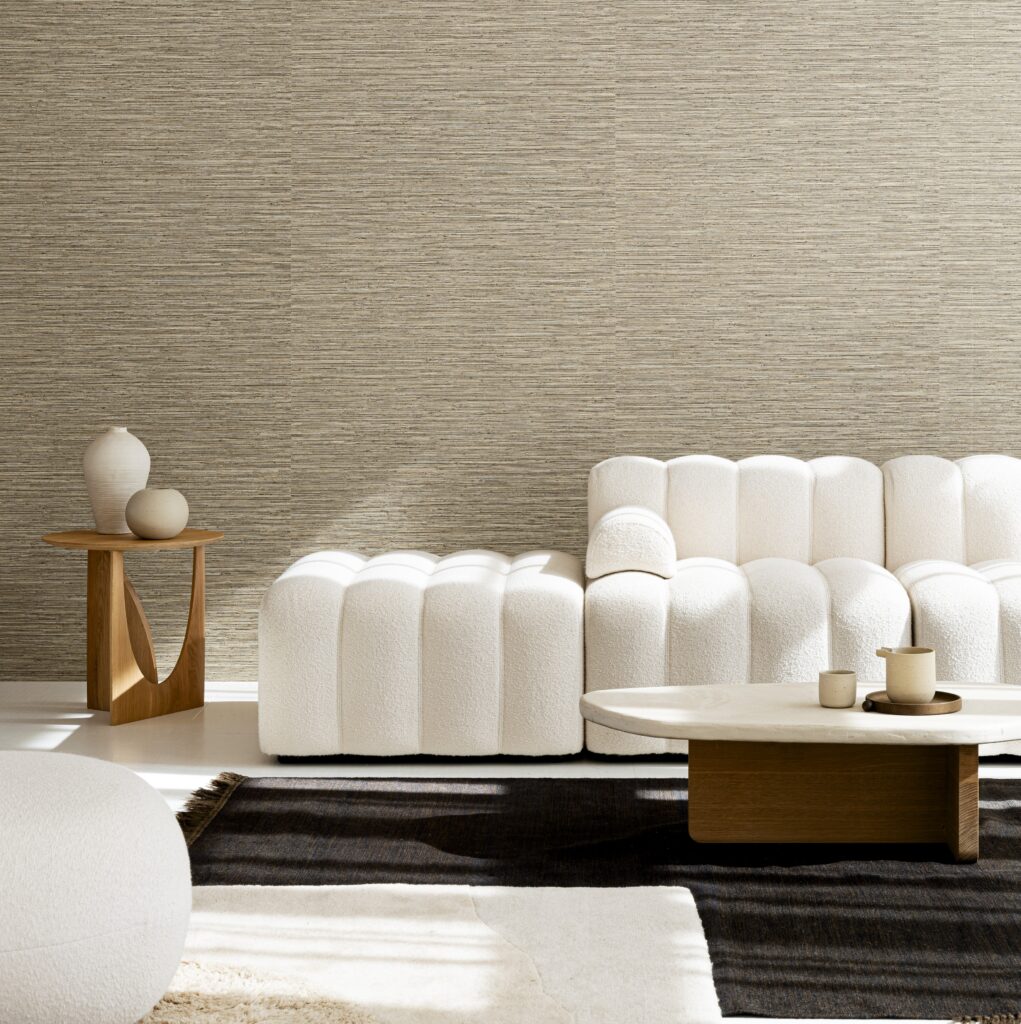 Stijlvolle woonkamer met Arte Matiz 73523A behang, een witte ribbelbank, minimalistisch houten bijzettafeltje en moderne salontafel.