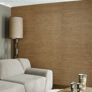 Moderne woonkamer met Arte Prismatic Gradient 52400 behang in natuurlijke bruintinten, grijze hoekbank en designlamp.