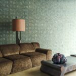 Moderne woonkamer met een bruine bank, sculpturale salontafel en Arte Reflect 52480 geometrisch patroonbehang.