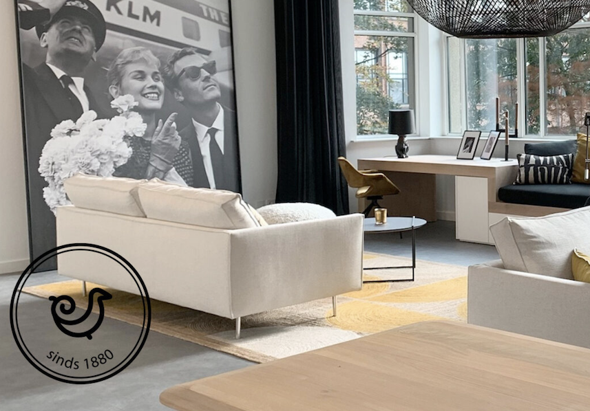 Stijlvol ingericht modern interieur van Buningh Interieur met lichte meubels, grote zwart-wit fotoprint en werkhoek bij het raam.
