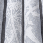 Gordijnstof met een wit silhouetpatroon van fluitenkruid en vogels op een grijze achtergrond uit de Cole and Son Cow Parsley collectie.