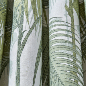 Close-up van het Cole and Son Palm Jungle linnen met een patroon van groene palmbladeren op een lichte achtergrond.